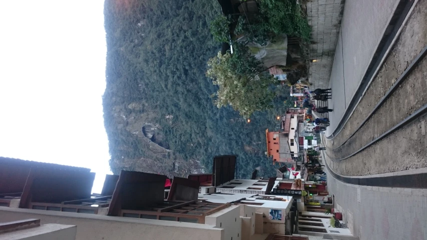 a narrow street with some buildings on one side and many people walking