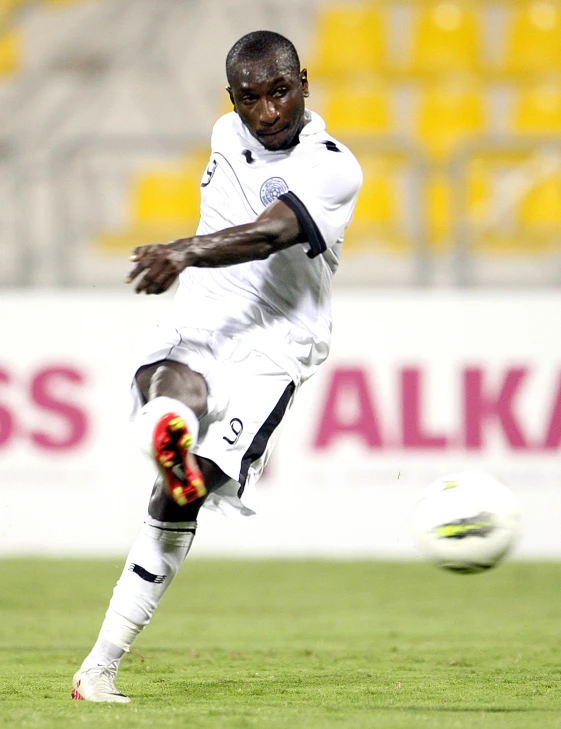 a man kicking a soccer ball while wearing red and black