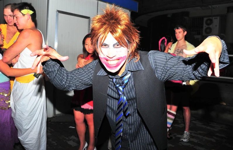 an adult man in a black shirt and tie is wearing clown makeup