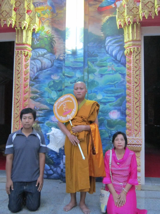 three people standing in front of an elaborate mural