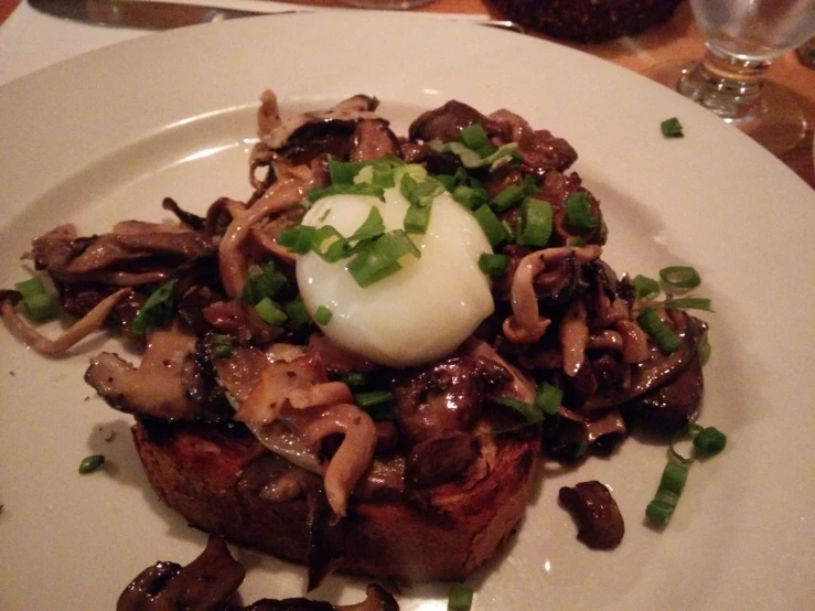 a white plate topped with meat and mushrooms covered in sauce