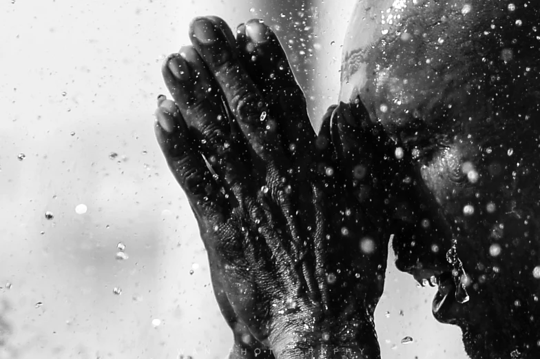 a man's hand reaching for a rain streaked glass
