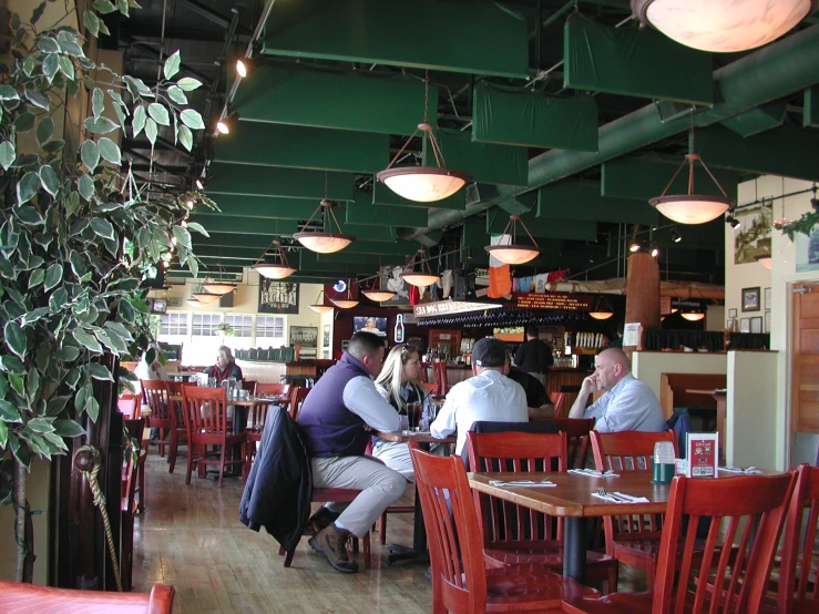 people sitting around tables and chairs in a restaurant