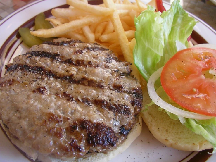 a hamburger with lettuce and tomato on the side