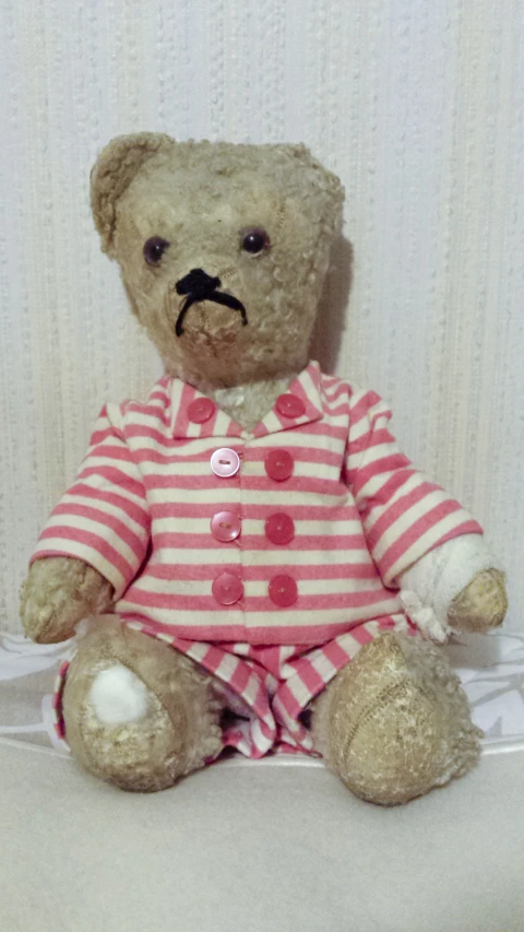 a brown teddy bear wearing a pink and white outfit