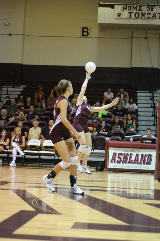 two female volleyball players playing basketball at an indoor game