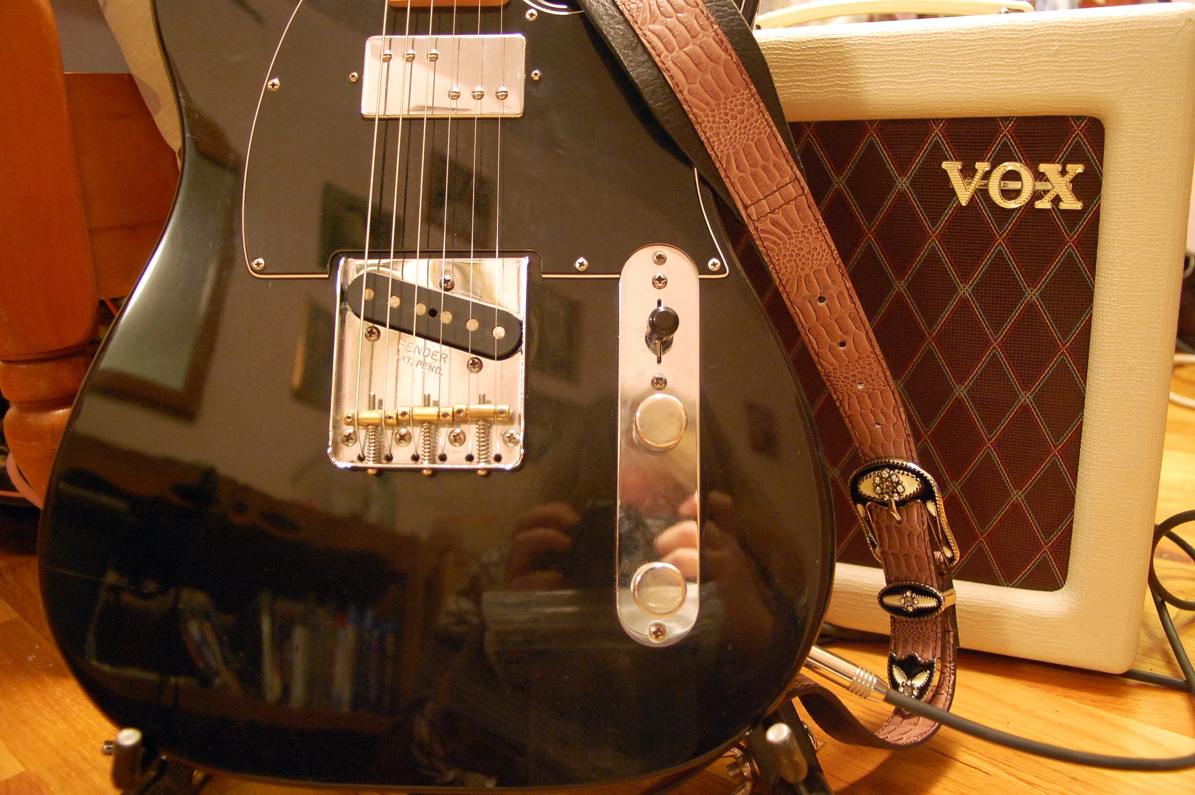 a black guitar sits beside an amp on a table