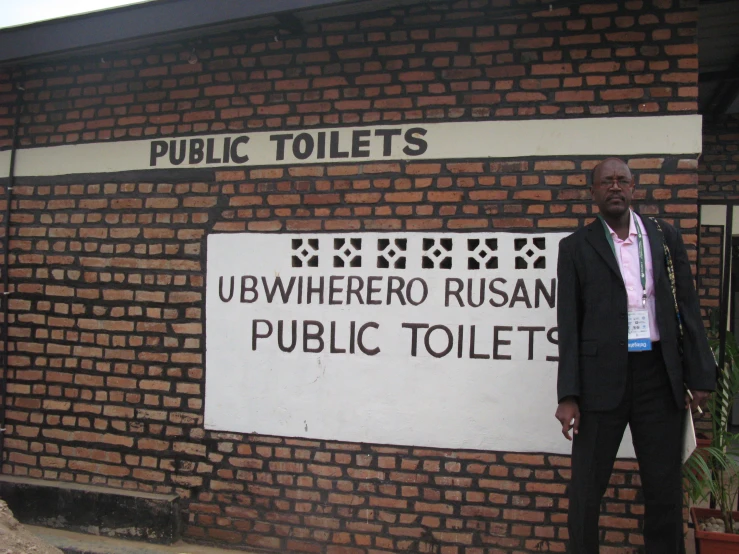 an older gentleman stands in front of the public toilets sign
