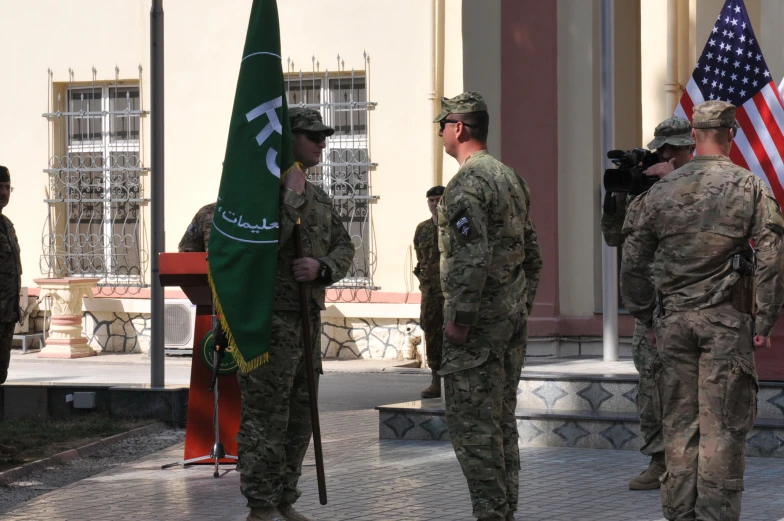 two military men standing next to each other holding american and afghan flags