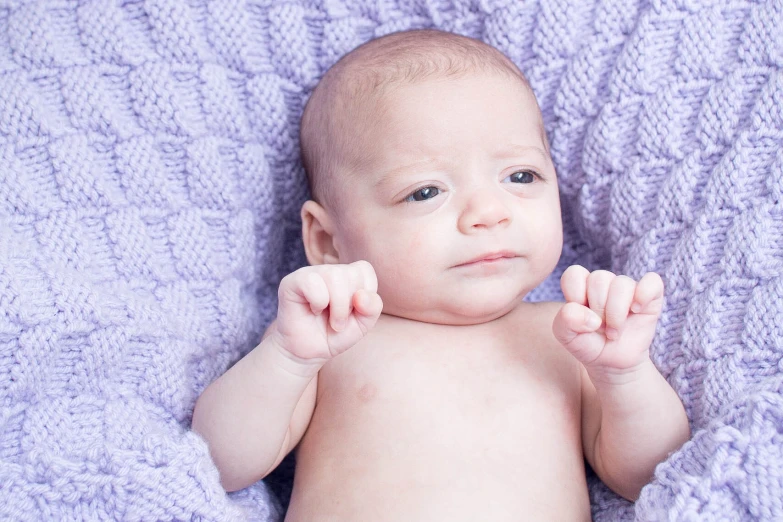 a baby is laying on a blanket looking at the camera