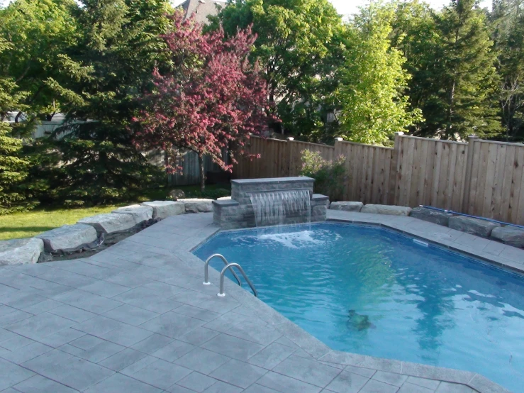 an empty backyard pool with a small waterfall