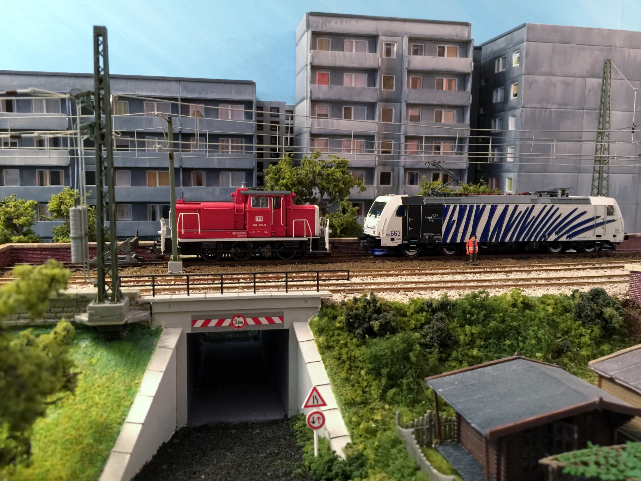 there are two red and white trains in front of the buildings