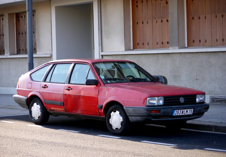 an older red car parked in front of a building