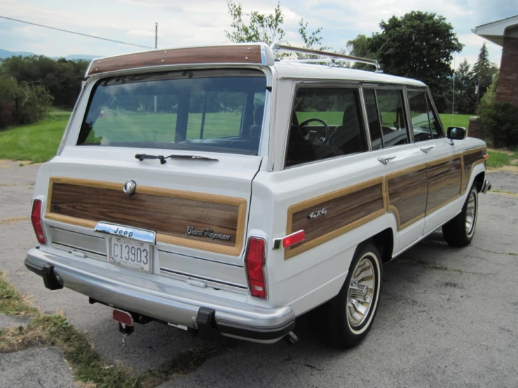 an old van with wooden paneling sits parked in a lot