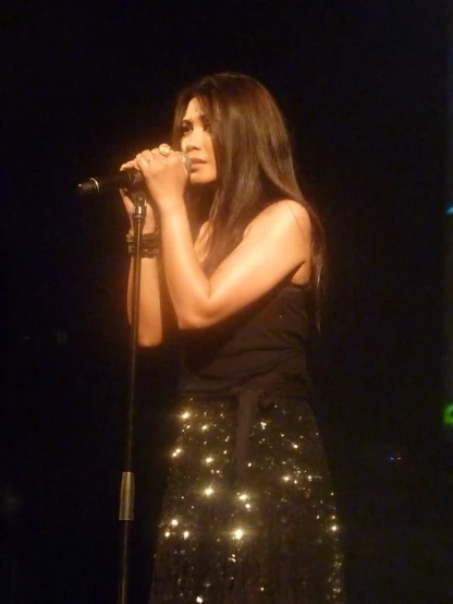 a woman in a shiny dress holds her hands to her face