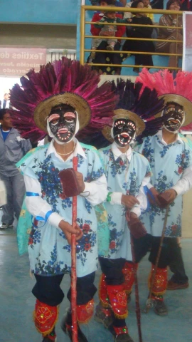 three men wearing colorful costumes and holding sticks