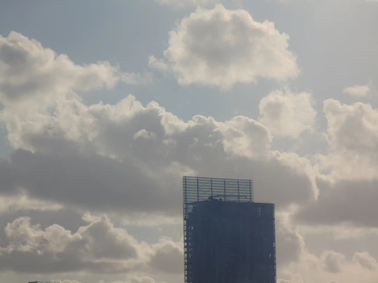 a tall building with some big clouds in the sky