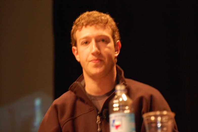 a man with glasses in front of his face next to a bottle