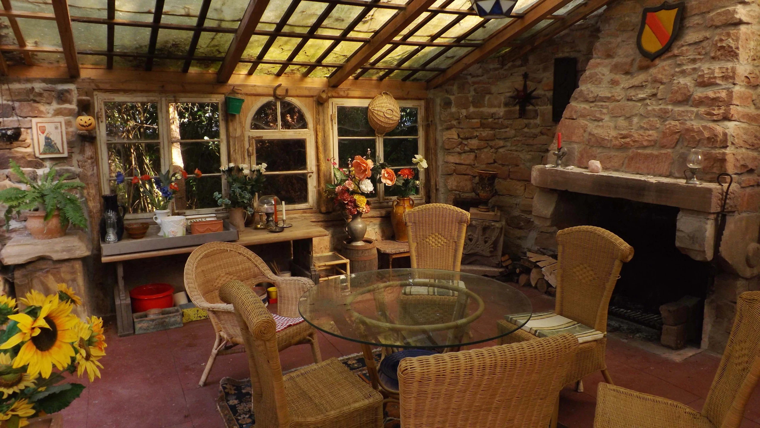 a wooden table topped with a glass top next to brown wicker chairs