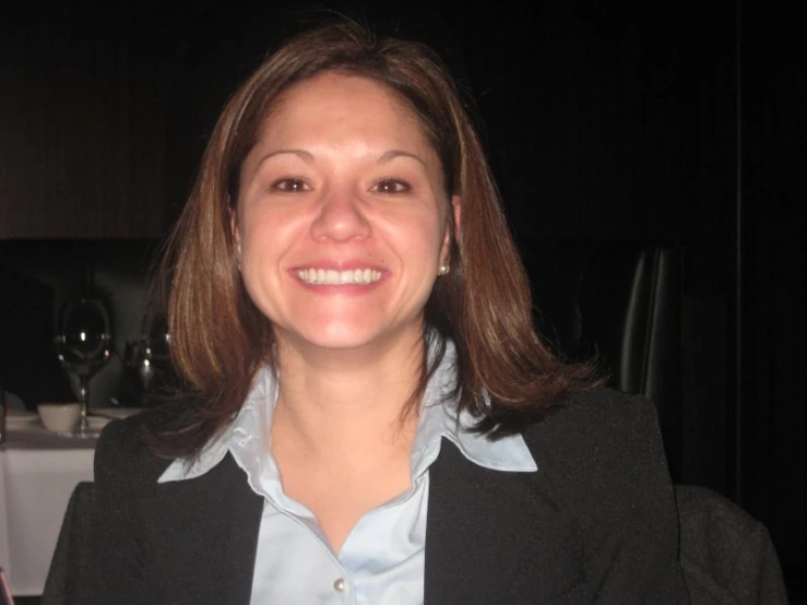 woman smiling at camera in dark room with white tablecloth