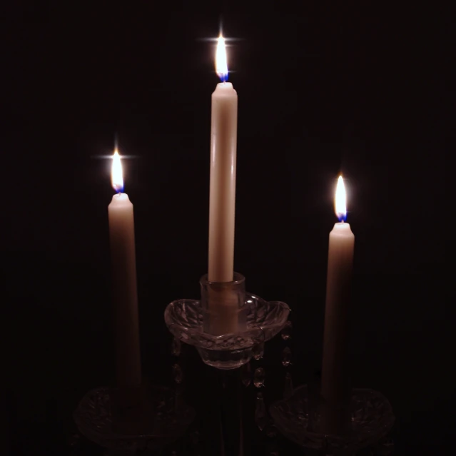 three white candles are lit next to each other