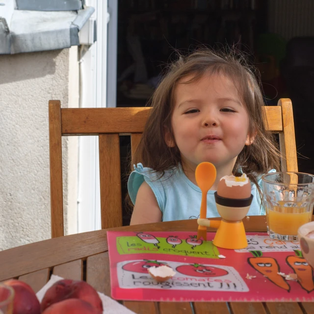 little girl sitting at an outside table eating