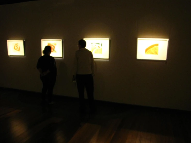 a couple is looking at the paintings in the dark