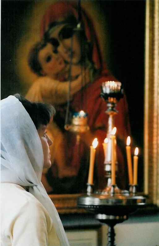 two women are in a room with candles and an image of jesus