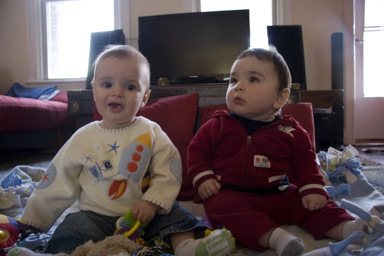 two toddlers sit in front of two couches