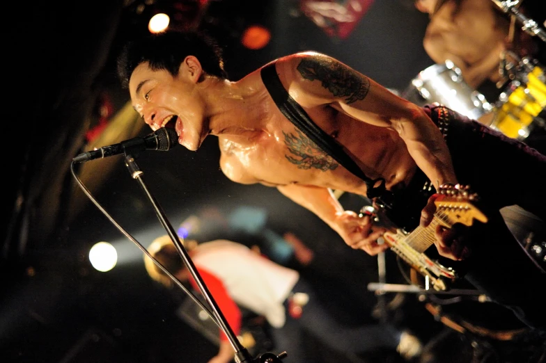 a shirtless male performing on stage with a microphone