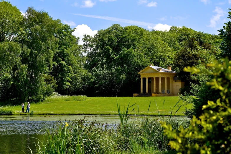 a house and lake in a park with some trees