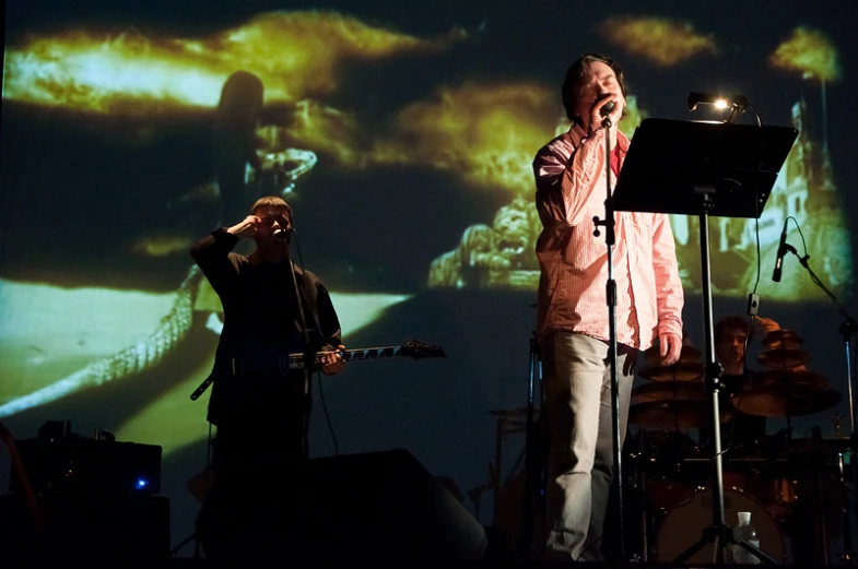 two men that are on stage singing into microphones