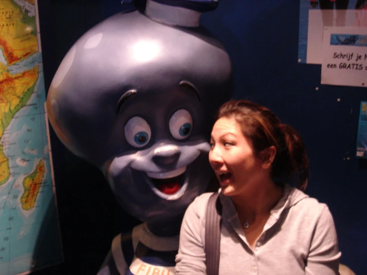 the woman is standing next to the smiling mascot