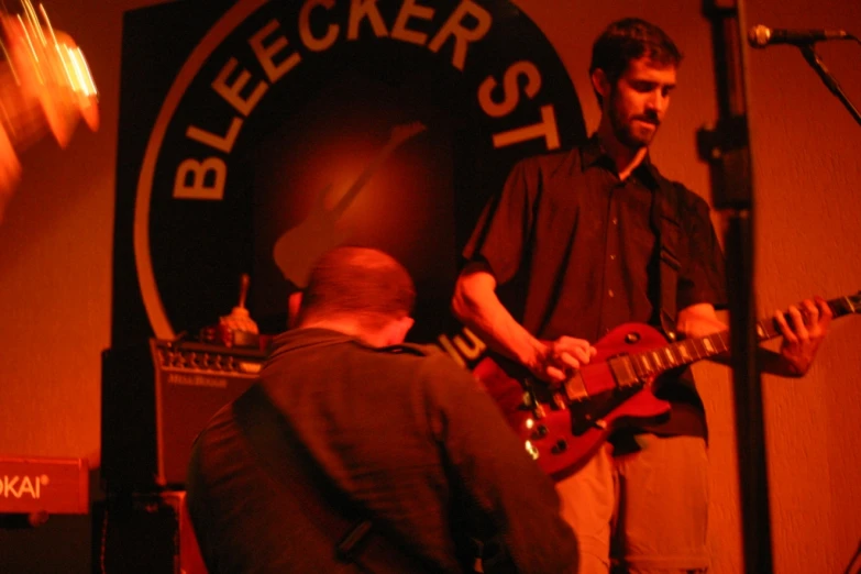 two people stand playing guitar and another plays bass