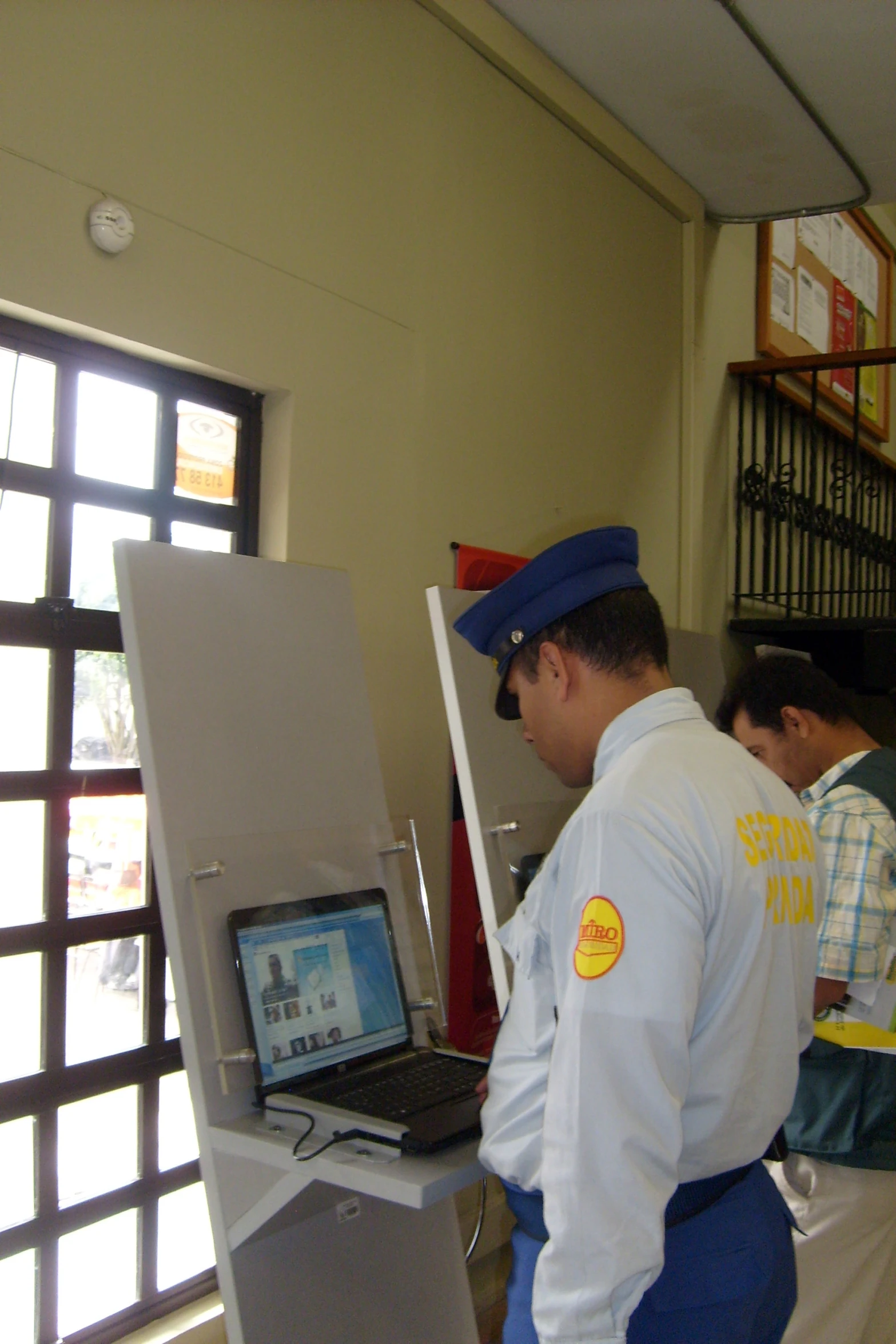 a man wearing a blue uniform and working on his laptop