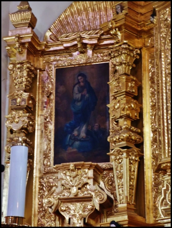 a painting in a gold framed church with ornate carvings