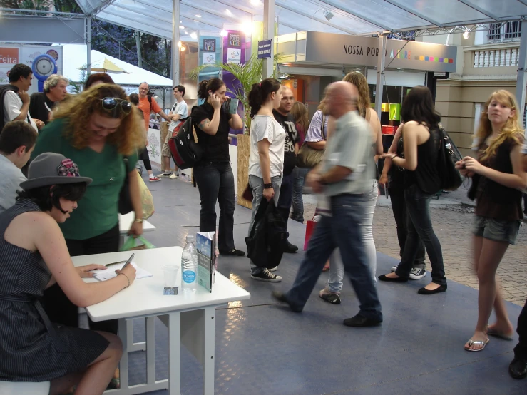 a group of people standing in line near a table with a laptop on it