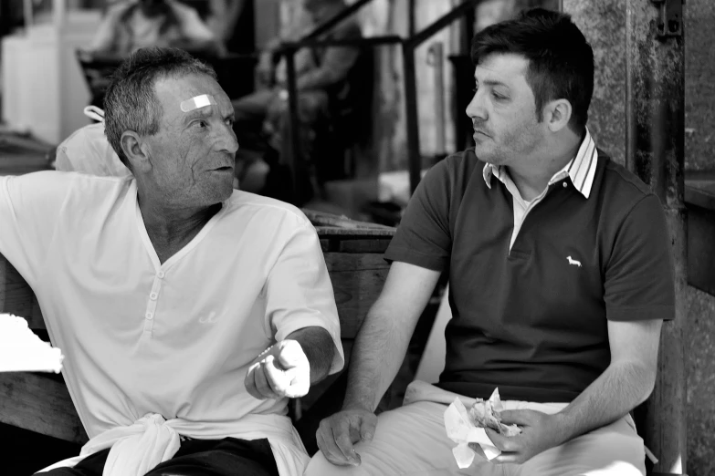 the two men are on a bench with food