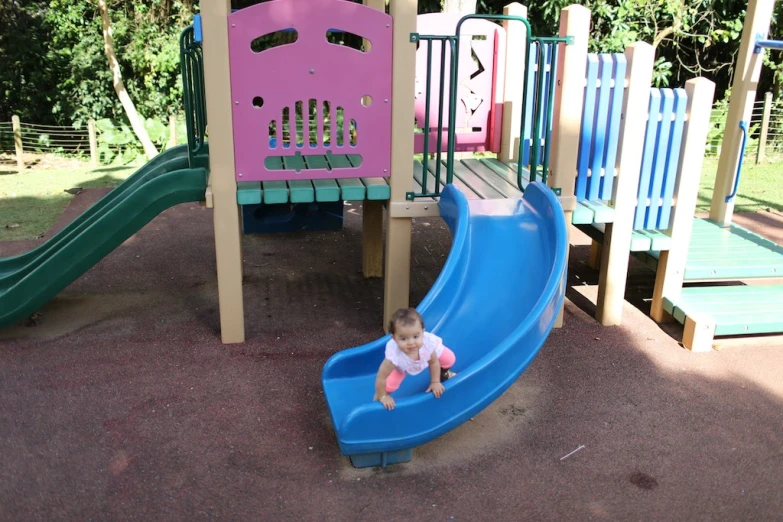 the little girl is playing in the colorful playground