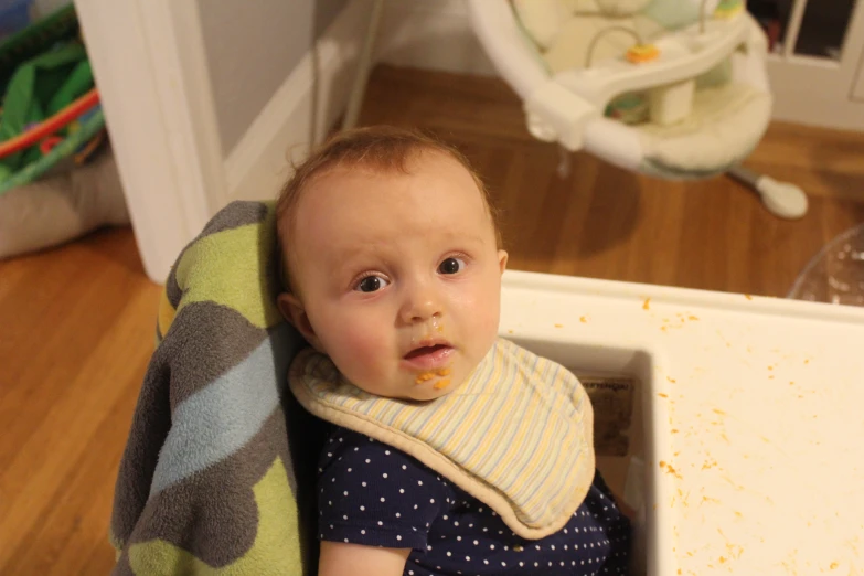 the baby is sitting in the highchair with a stuffed animal on its neck