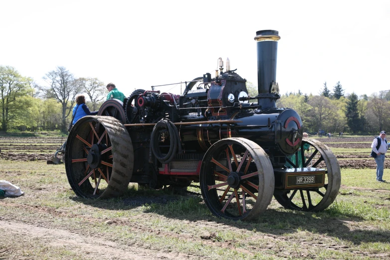 a man standing by an old tractor in a field