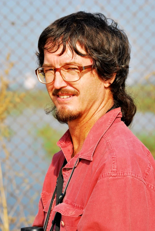 a man with eye glasses and mustache wearing a camera