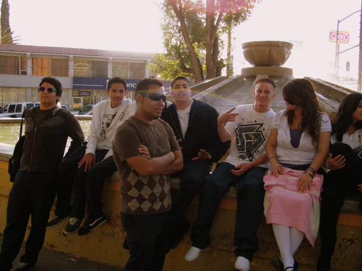 some friends sitting together on a wall in front of a fountain