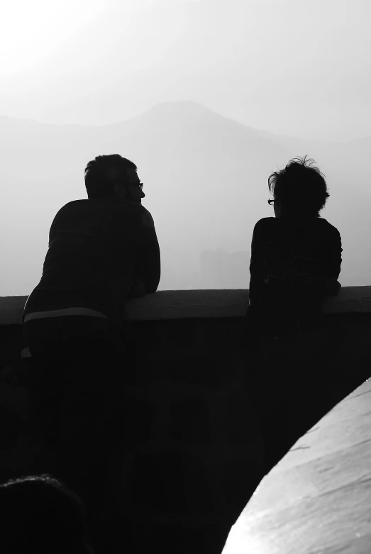 two people sitting on a bench with mountains in the background