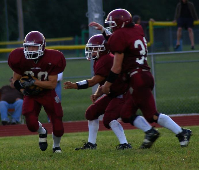 there are two young football players in maroon uniforms