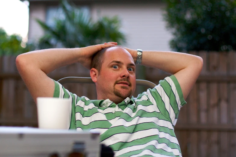 a man in a striped shirt sitting in front of a table