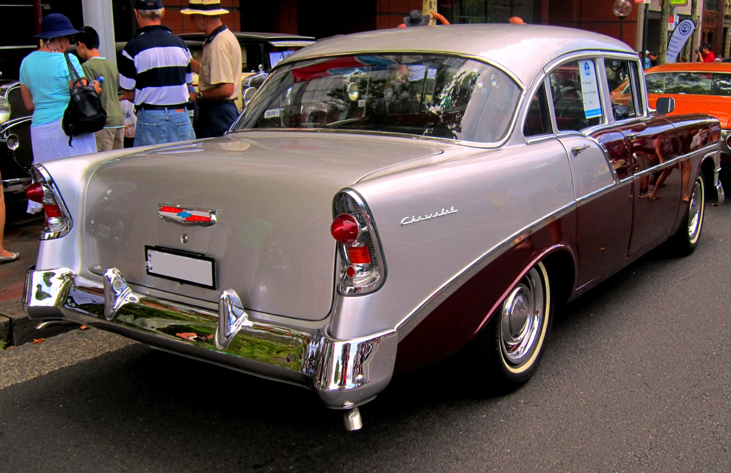 a classic car parked on a street with people