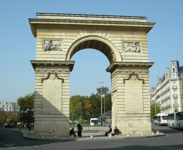 two people walking in between two large stone archways