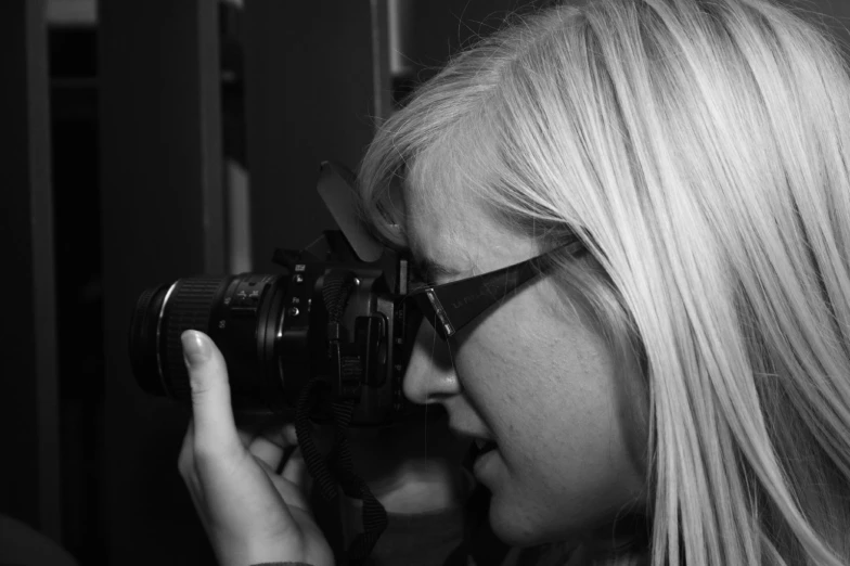 a girl with glasses looking at soing in a camera