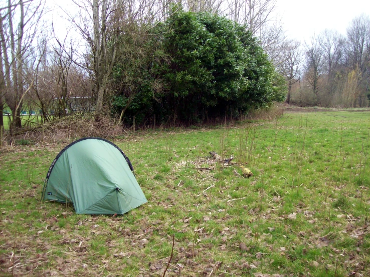 a green tent pitched up on a grass field